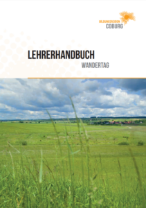 Titelbild des Lehrerhandbuches der Bildungsregion Coburg mit der Unterüberschrift: Wandertag. Darunter ist ein Bild von offener Landschaft mit grünen Wiesen zu erkennen.