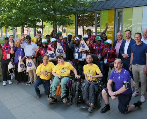 Die Delegation aus Togo winkt zusammen mit mehreren Rollstuhlfahrern, dem Organisationsteam aus Coburg, Martin Stingl und Can Aydin in die Kamera.